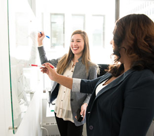 Two people working together at a whiteboard