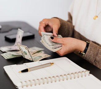 Woman counting money next to a ledger